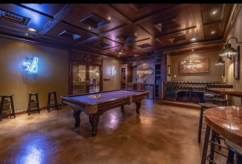 Interior of a cozy bar with a pool table, neon lighting, wooden furniture, and decor, creating a warm and inviting atmosphere.